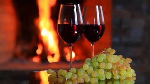 Two glasses of red wine with grapes near the fireplace Stock Footage 83802160