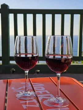 Two Glasses of Red Wine Overlooking a Scenic Ocean View Foto stock