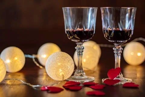 Two glasses of red wine, red hearts and lights around. Valentine, romance con Stock Photos
