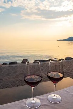 Two glasses of red wine on a restaurant table with a scenic sunset view Stock Photos