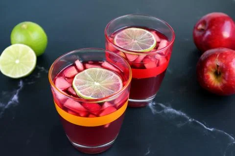 Two Glasses of Red Wine Sangria on the Table with Limes and Apples 스톡 사진
