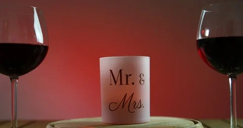 Two glasses of red wine standing on a table with candle on the wooden platform Stock-Footage 91632174