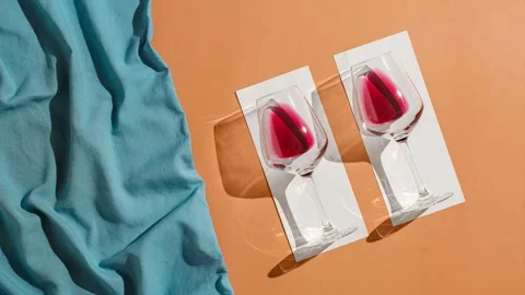 Two glasses of red wine on white towels sunbathe on the beach. Stock Footage 220601294