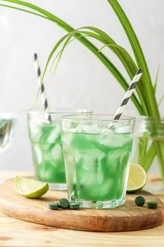 Two glasses of refreshing lemonade with chlorella and lime on a wooden table. Stock Photos