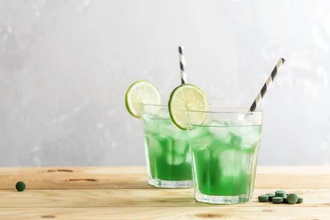 Two glasses of refreshing lemonade with chlorella and lime on a wooden table. Foto stock