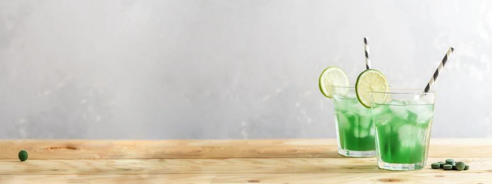 Two glasses of refreshing lemonade with chlorella and lime on a wooden table. 스톡 사진