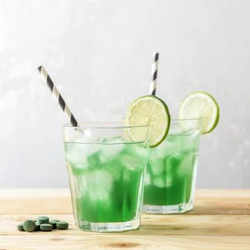 Two glasses of refreshing lemonade with chlorella and lime on a wooden table. Stock Photos