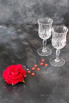 Two glasses, a rose and small red heart on a dark background Stock Photos