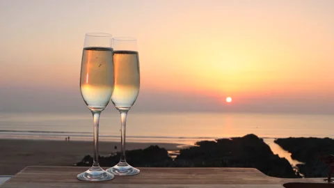 Two Glasses of Sparkling White wine as sun set's at English beach Stock Footage 172482173
