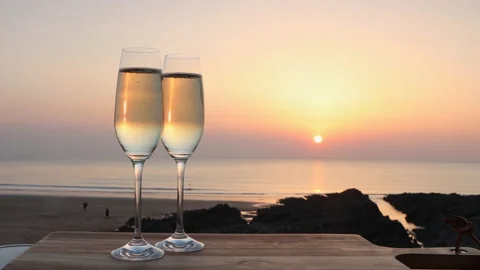 Two Glasses of Sparkling White wine as sun set's at English beach Stock Footage 172482323