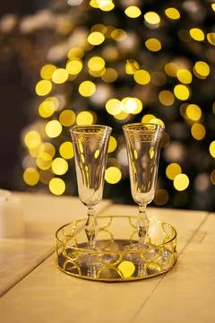 Two glasses stand against the background of Christmas lights Stock Photos