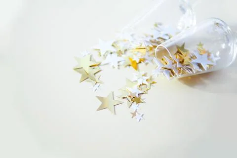 Two glasses on the table and falling confetti stars of white and gold color o Stock Photos