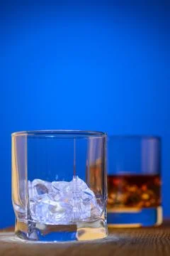 Two glasses on the table, first with pieces of ice and second with drink on a 스톡 사진