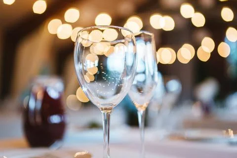 Two glasses on table on white tablecloth on blurred warm lights background Stock Photos