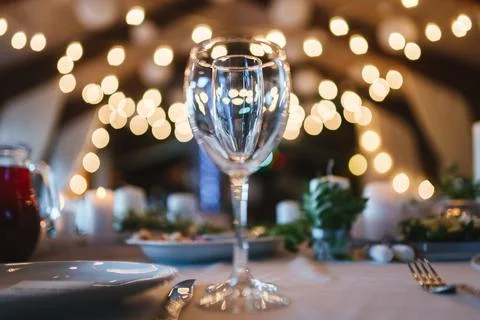 Two glasses on table on white tablecloth on blurred warm lights background Stock Photos