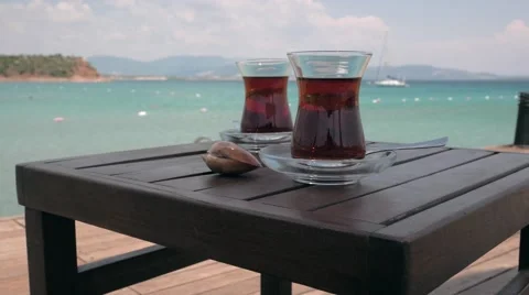 Two glasses of turkish tea on the table with anchored sailing yacht in the sea Stock Footage 53138356