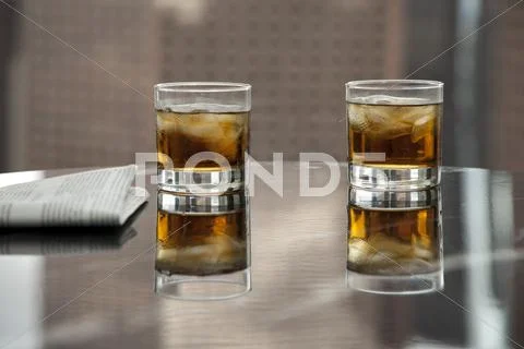 Two Glasses Of Whiskey And Ice On A Table