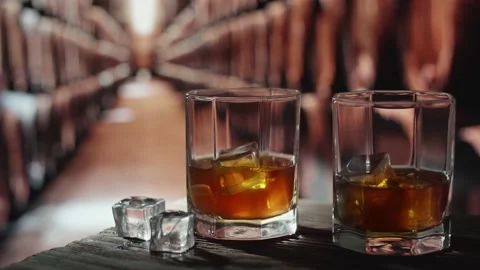 Two glasses of whiskey with ice are on a wooden table. Stock-Footage 145288845