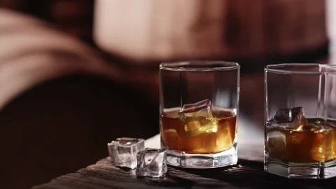 Two glasses of whiskey with ice are on a wooden table. Vidéo 145289016