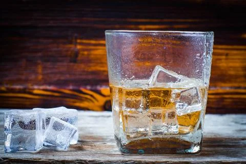Two glasses of whiskey with ice cubes served on wooden planks. Vintage counte Stock Photos