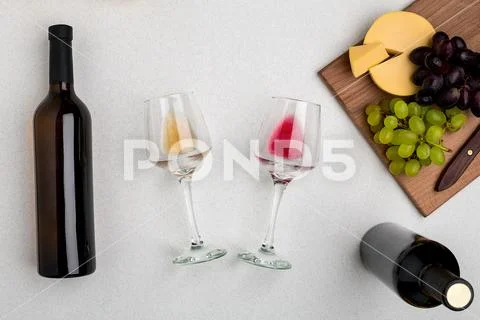 Two glasses of white and red wine, cheese and grapes. Top view Stock Photos