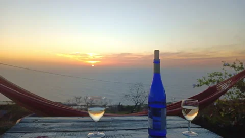 Two glasses of white wine and bottle on a rural wooden table at sunset Stock Footage 170524647