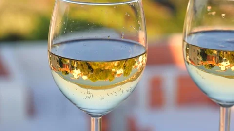 Two glasses with white wine close-up, beautiful white houses with tiled roof Stock Footage 124701081