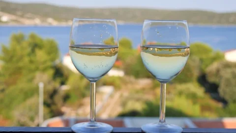 Two glasses with white wine close-up, beautiful white houses with tiled roof Stock Footage 124701160