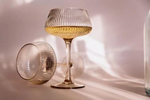 Two glasses with white wine placed on light beige background with shadows Stock Photos