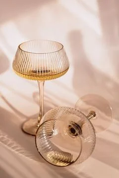 Two glasses with white wine placed on light beige background with shadows Stock Photos