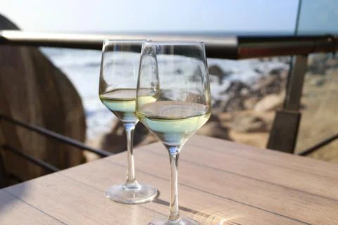 Two glasses of white wine on a table overlooking the ocean. Stockfoto's