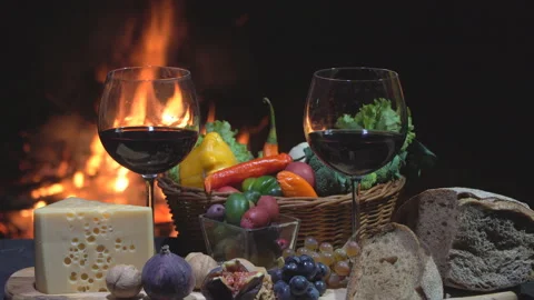 Two glasses of wine, cheese, bread and fruit on fire background, dolly shot Stock Footage 96483791