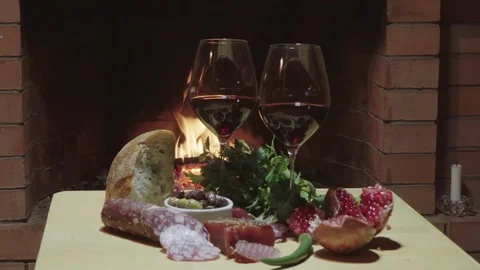 Two glasses of wine, cheese, bread and fruit on fire background, dolly shot Stock Footage 124096150