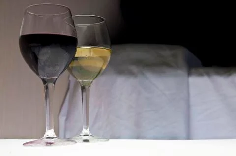 Two glasses of wine next to bed. Romantic evening. Stock Photos