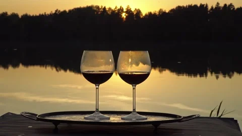 Two glasses of wine at sunset on a forest lake Stock Footage 139810081