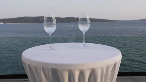 Two glasses of wine on the table against the backdrop of the sea and mountains Stock Footage 183464249