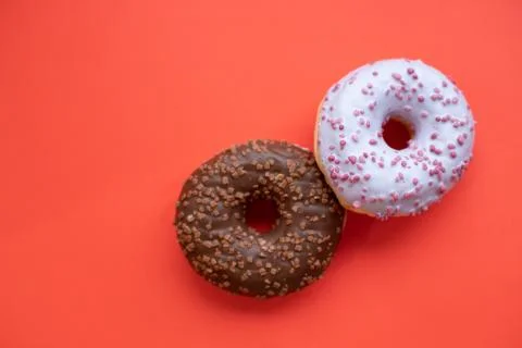 Two glazed donuts isolated on red background.pastel color,pink and brown sweet Stock-Fotos