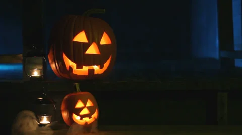 Two glowing jack-o-lanterns and two candles sit on porch steps with eerie smoke Stock Footage 30560093