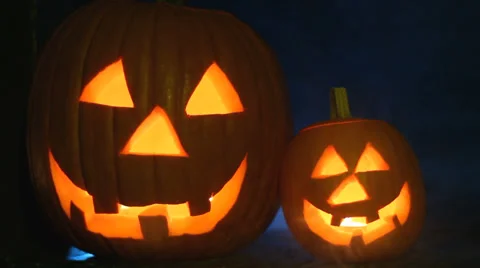 Two glowing jack-o-lanterns sit on porch with eerie smoke, medium close up Stock Footage 30560903