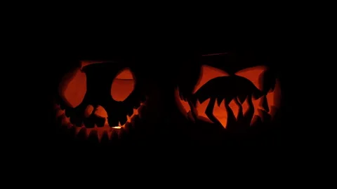 Two Glowing Jack-o'-Lanterns Flickering Against Black Background Video stock 342563230