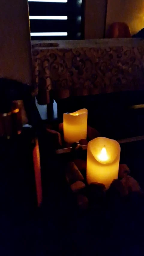 Two Glowing Pillar Candles Surrounded by Decorative Rocks Stock Footage 321972841