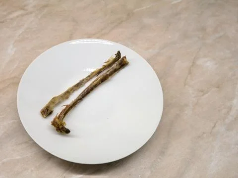 Two gnawed bones without meat stand on a white plate on the kitchen table Foto stock