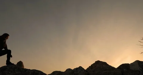 Two go on rocks, against a sunset Stock Footage 74749323