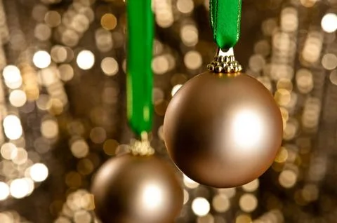 Two gold christmas baubles in front of a gold glitter background Stock-Fotos
