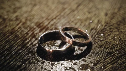 Two gold rings are lying on the table and they are illuminated by dynamic light Stock Footage 267742097