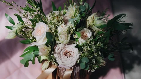 Two gold rings lie on the surface of a bouquet of fresh flowers Stock Footage 172462028