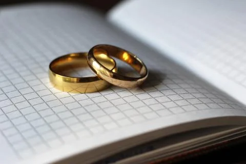 Two gold wedding rings and a paper notebook Stock Photos