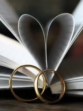 Two gold wedding rings and a heart made of paper pages Stock Photos