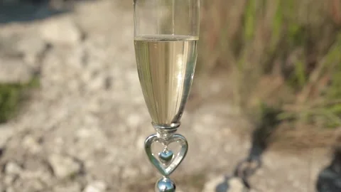 Two gold wedding rings fall into a glass of champagne. Stock Footage 170607321