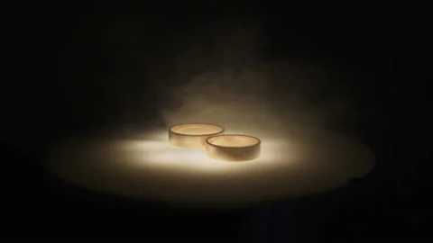 Two gold wedding rings lie on luminous surface. Jewelry is enveloped in smoke. 動画素材 183395286